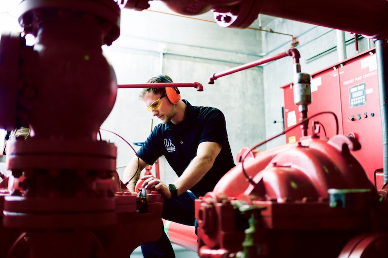 man in red boiler room doing preventive maintenance