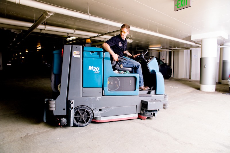 man driving sweeping machine in parking garage