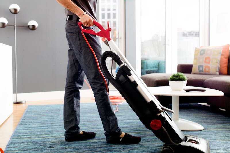 man vacuuming apartment as part of cleaning services