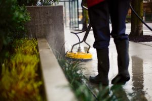 man cleaning sidewalk using sweeping machine