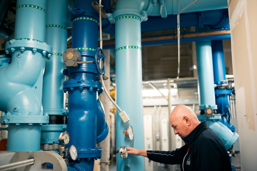 man checking nozzle in blue pipe room