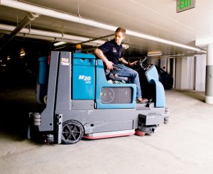 Man riding sweeping vehicle in parking garage